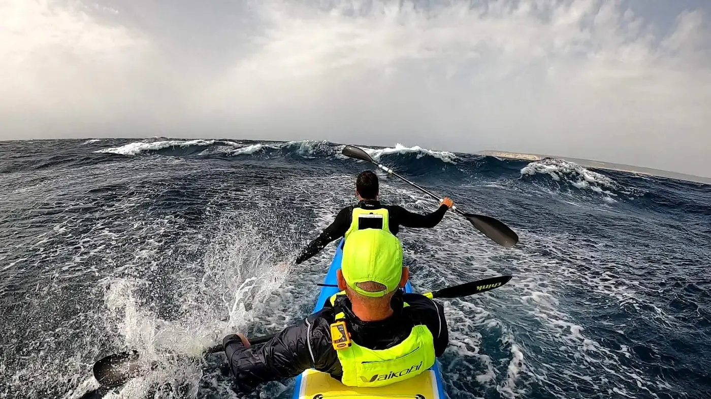 Kayakistas remando entre olas en el Estrecho de Gibraltar durante una experiencia downwind de Strait of Emotions